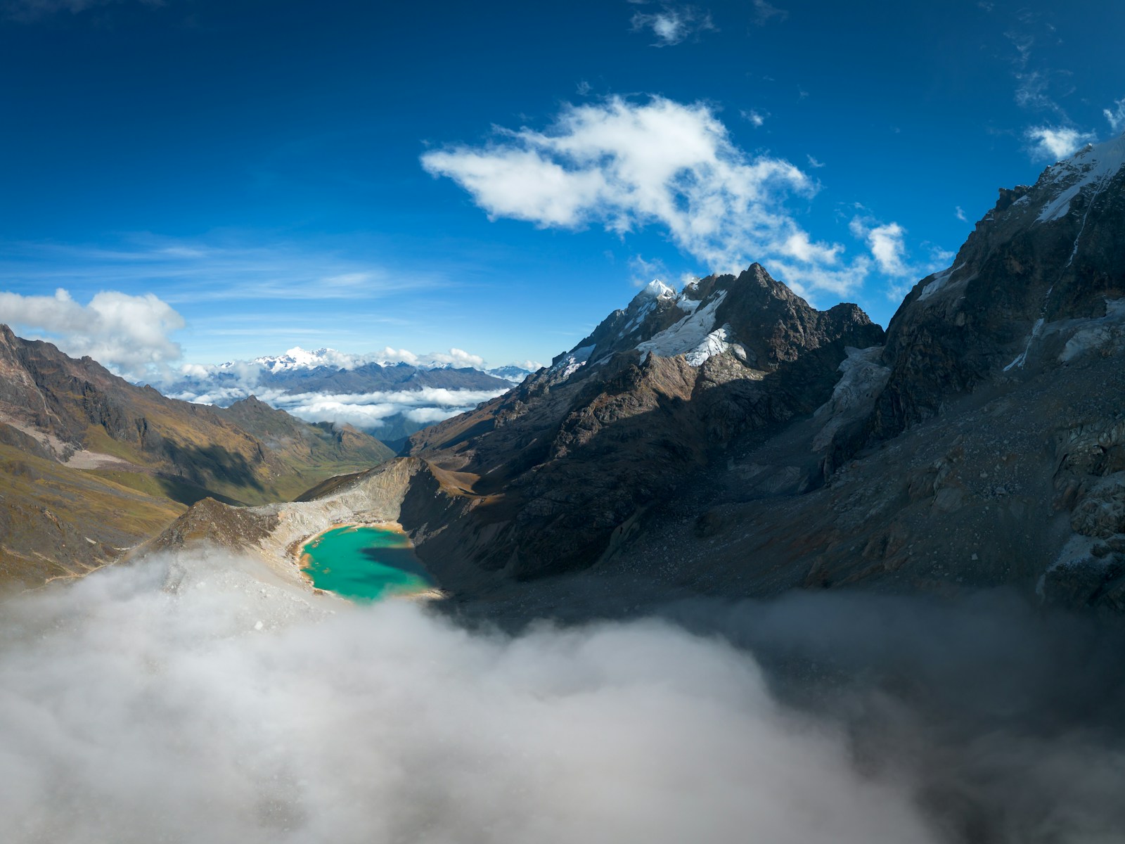 a mountain range with a lake surrounded by clouds