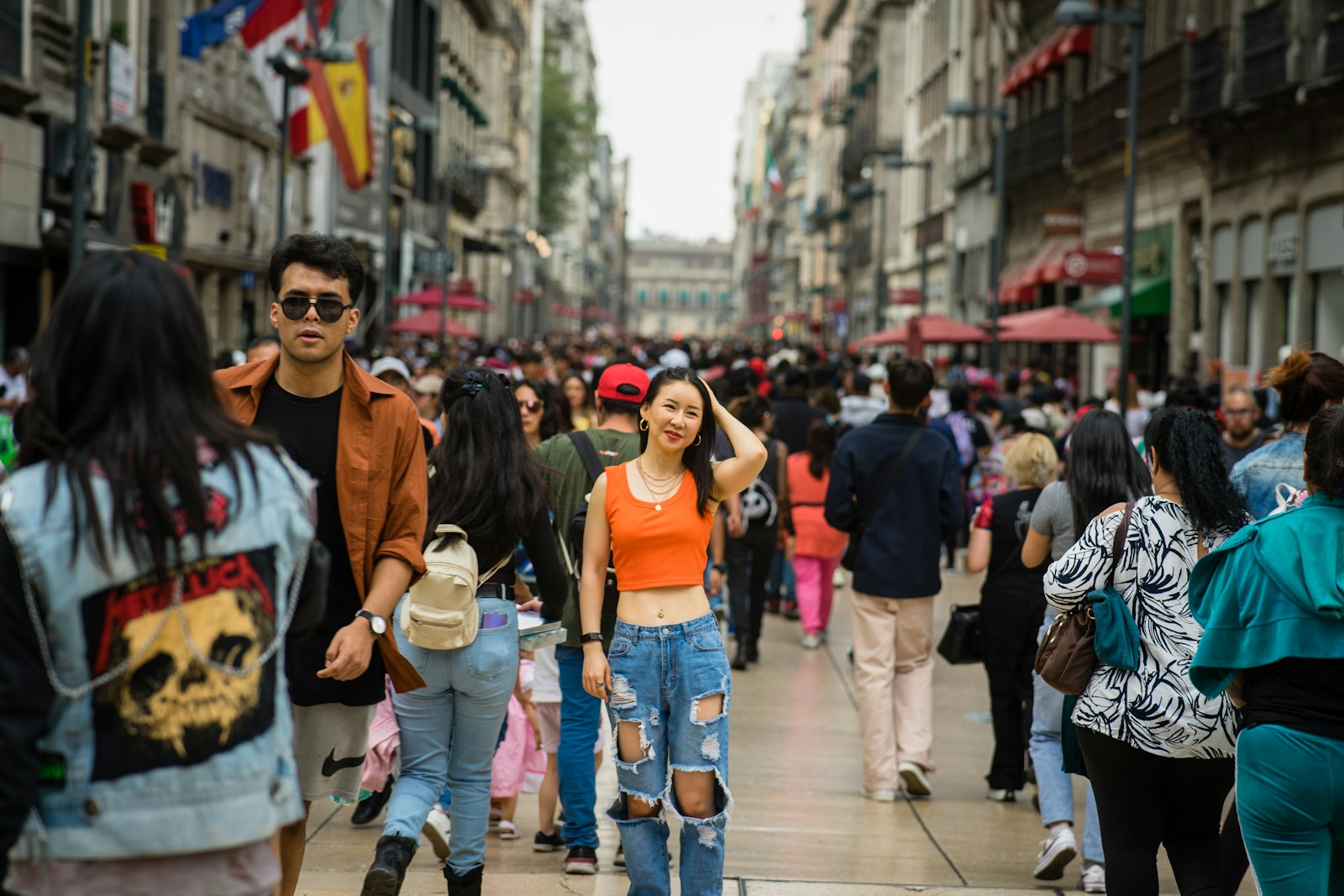 a group of people walking down a street next to tall buildings